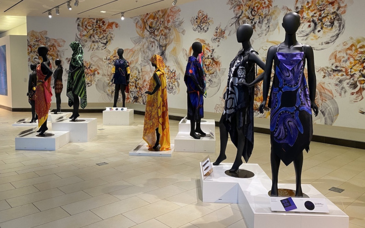dark mannequins in colorful fabrics stand in an atrium