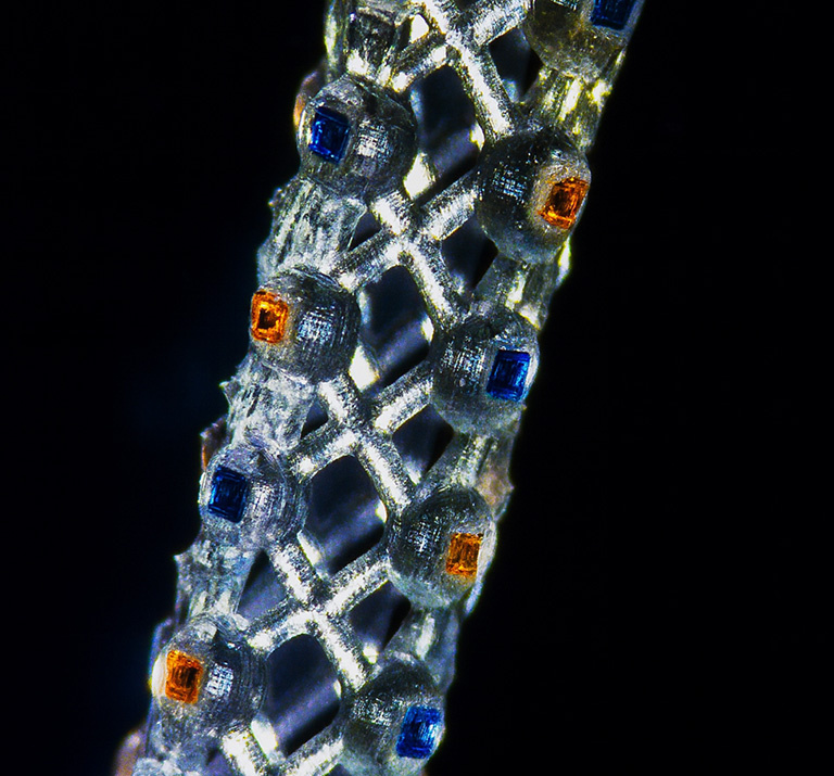 Cylinder shining like white gold and in the lattice orange and blue jewels