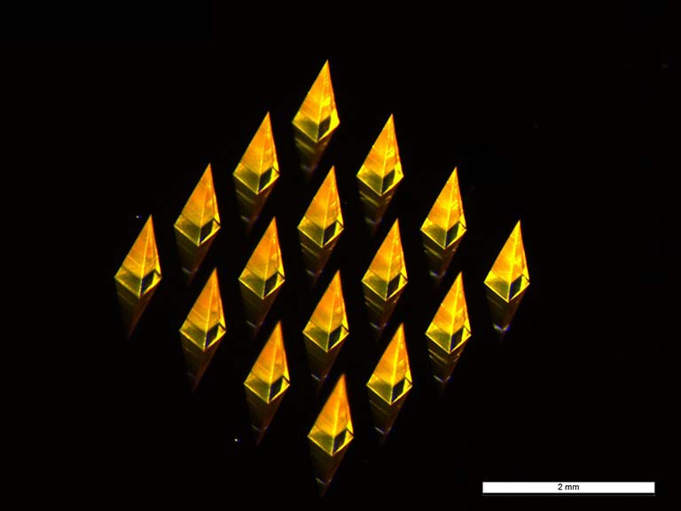 translucent gold pyramids reflecting on a silicon chip, 2 millimeter scale bar in the bottom right corner