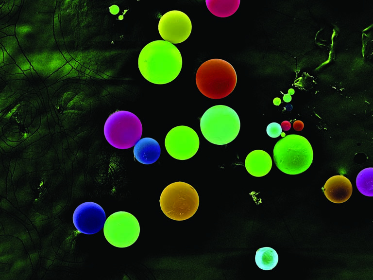 fluorescently colored spheres on a mottled background