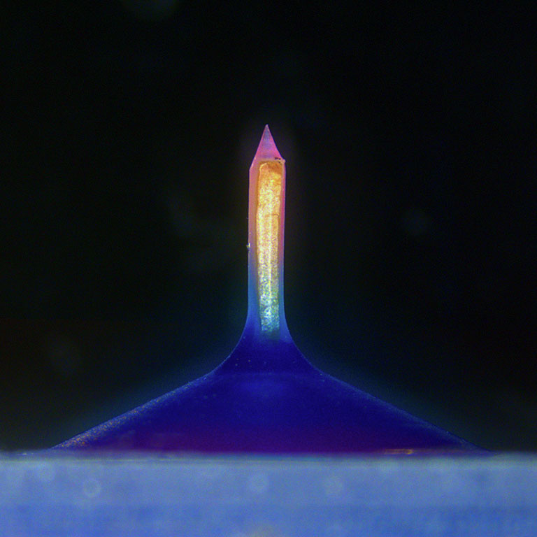 A glowing column with a gradient of pink to yellow to cyan mounted on a triangular indigo base
