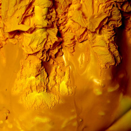 a golden yellow surface layers over itself, rough at the top, smooth at the bottom