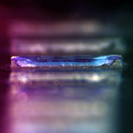 A iridescent column of pinkish polymer layers. The third layer is in focus; the others are fuzzy.