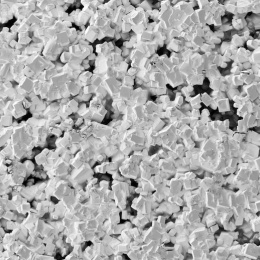 Black and white image of a pile of small square crystals. Appearing like square sponges pressed against glass. 